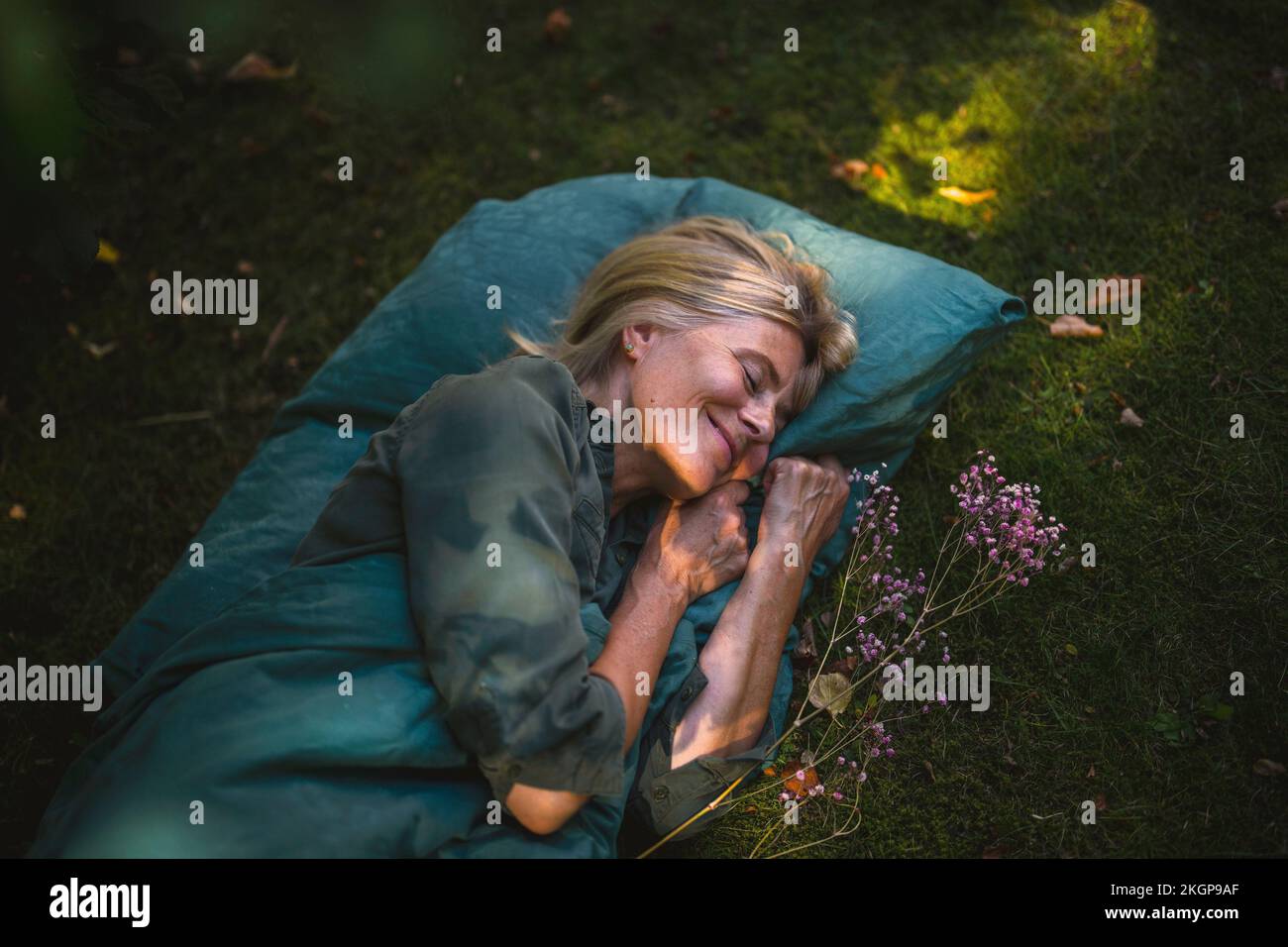 Donna matura sorridente che dorme in giardino Foto Stock