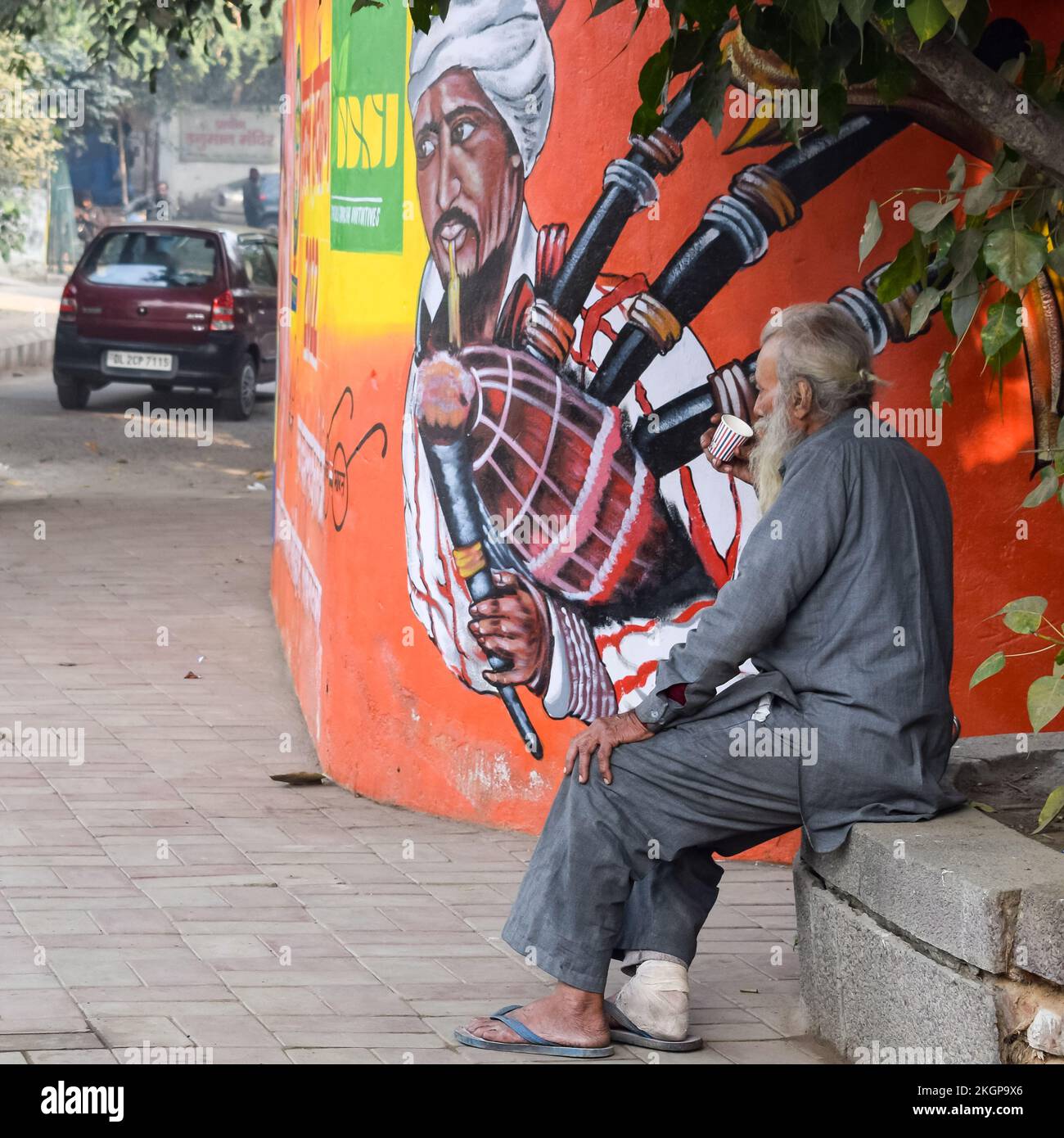 New Delhi, India - 25 dicembre 2021 - Vecchio povero uomo bere tè durante la stagione invernale in vecchia strada di Delhi, Delhi Street Fotografia Foto Stock