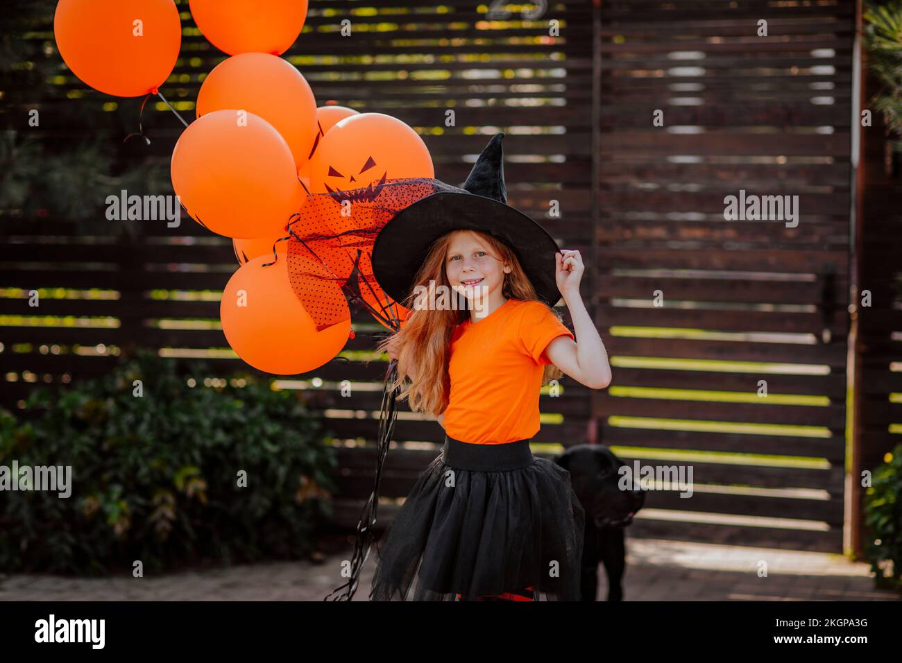 Ragazza che indossa un cappello da strega con palloncini arancioni Foto Stock
