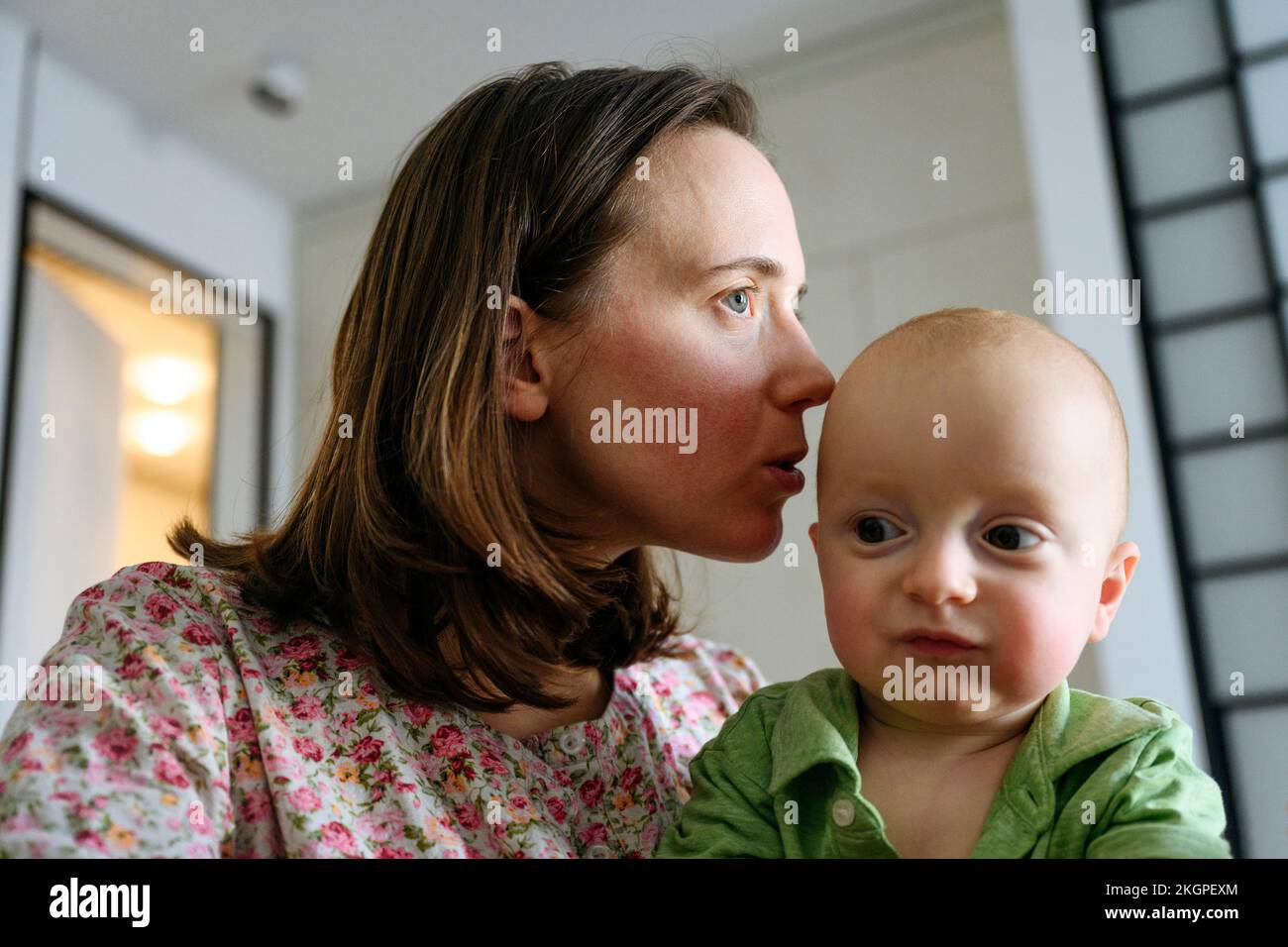 Madre baciando il ragazzo carino in testa a casa Foto Stock