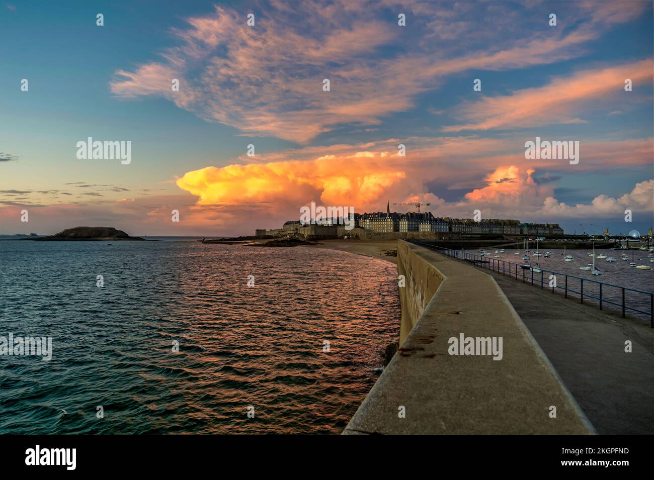 Molo verso la città vecchia di St Malo in mezzo al mare al tramonto Foto Stock