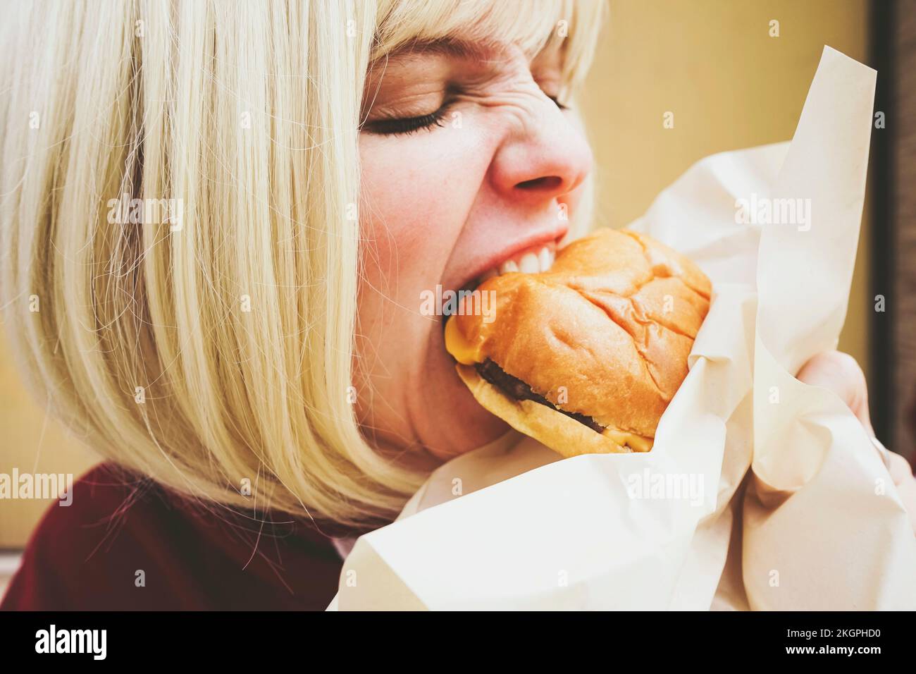 Donna con capelli biondi mangiare hamburger Foto Stock