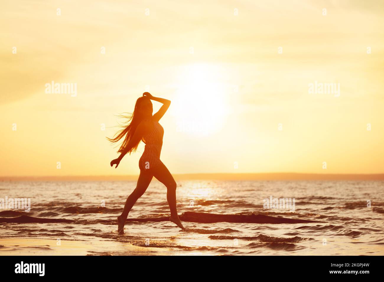 Felice ragazza giovane è a piedi al tramonto spiaggia di mare Foto Stock