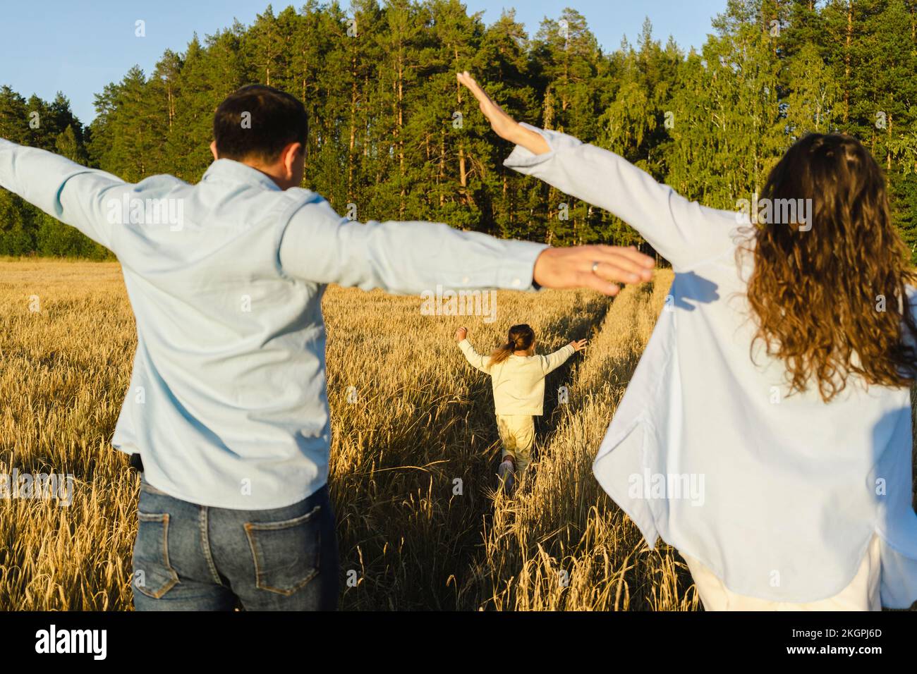 Genitori spensierati con figlia che cammina insieme nel campo Foto Stock