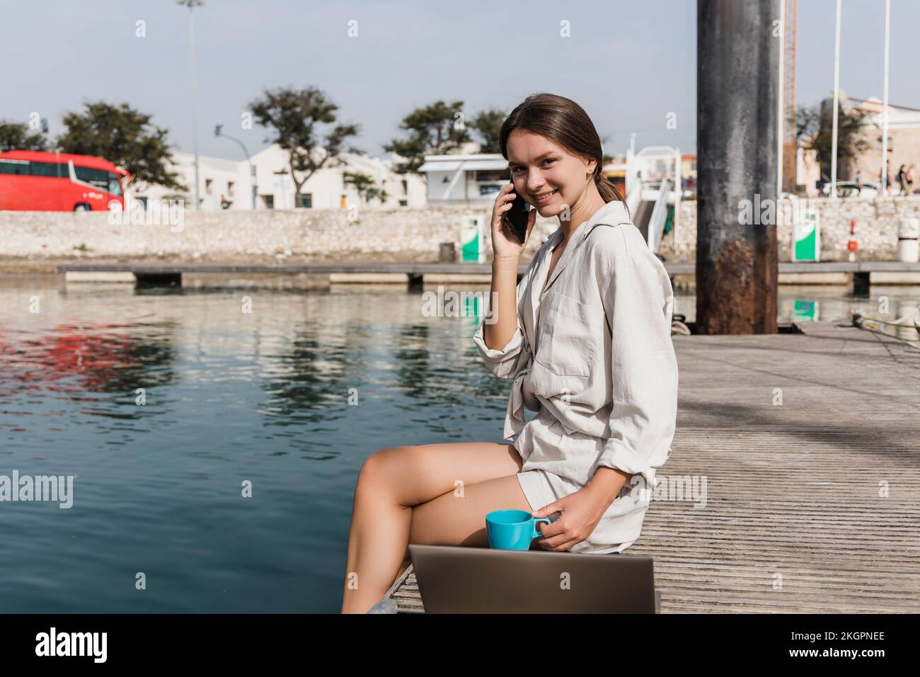 Felice giovane donna che parla sullo smartphone al molo Foto Stock