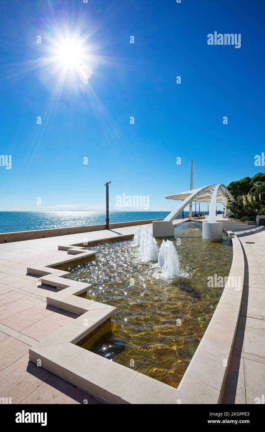 Italia, Friuli Venezia Giulia, grado, Sole che splende sulla moderna fontana sul lungomare Foto Stock