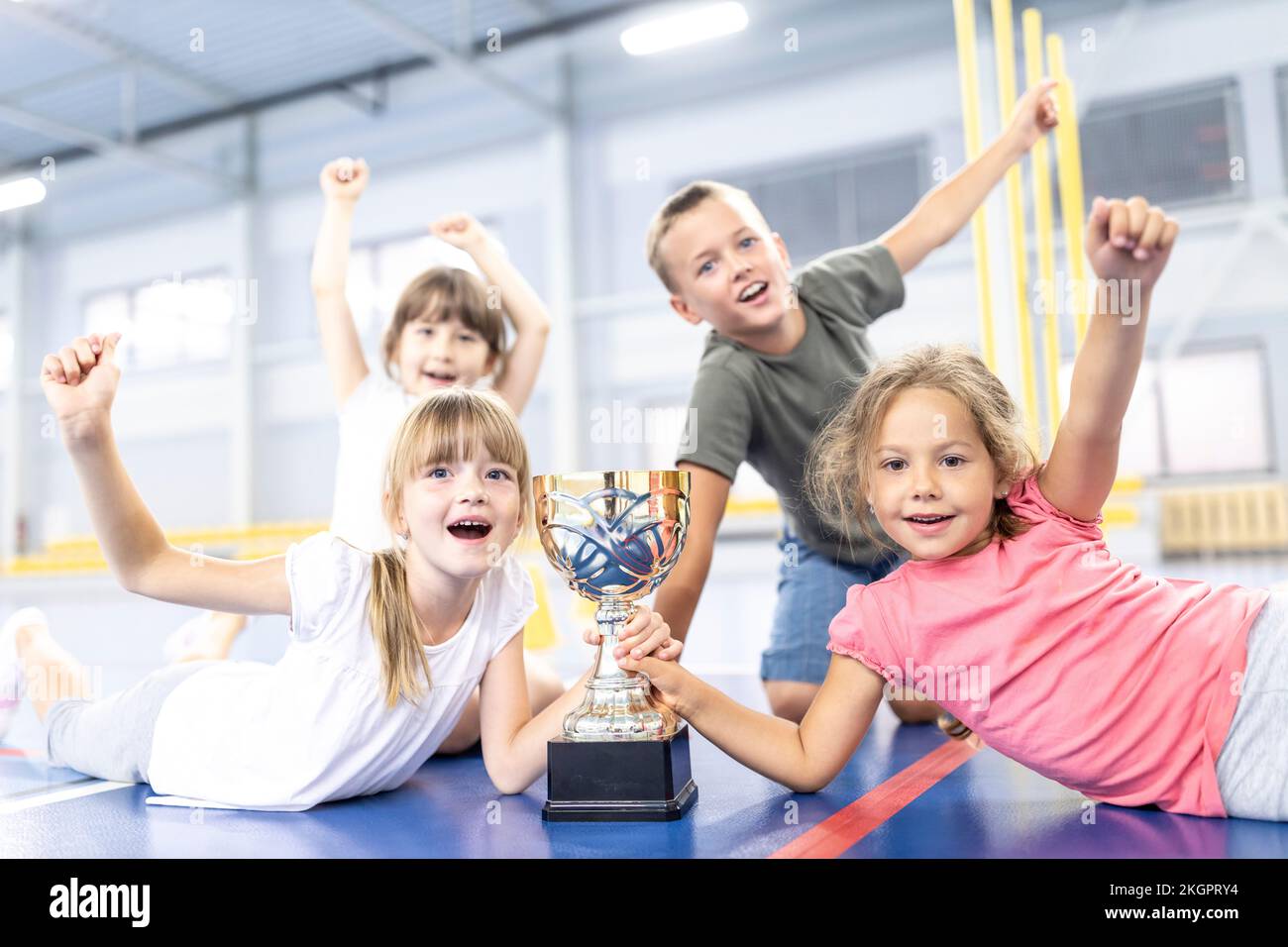 Studenti che si acclamano con l'altro tenendo trofeo a scuola campo sportivo Foto Stock