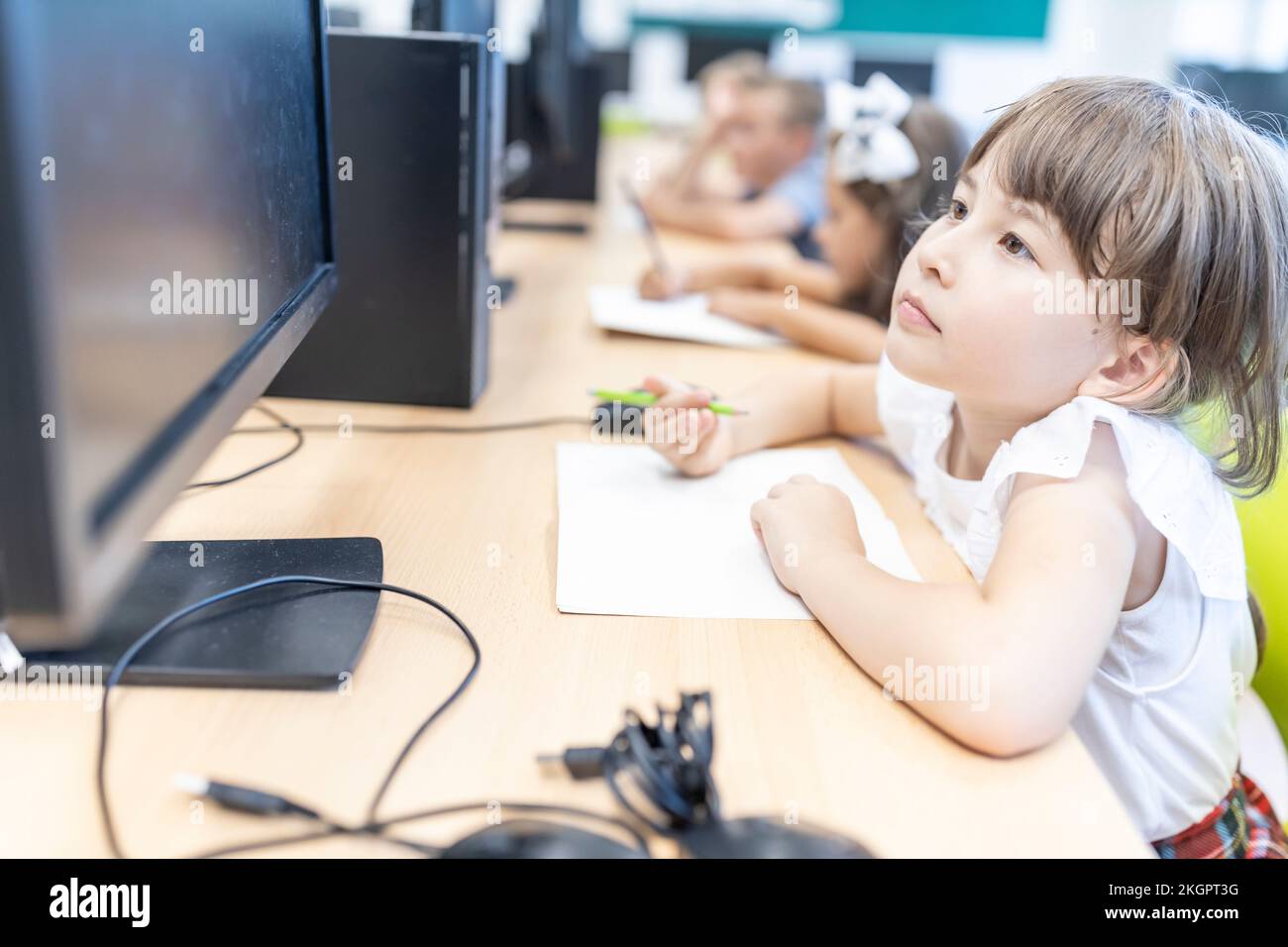 Studentessa elementare che guarda lo schermo del desktop in classe Foto Stock