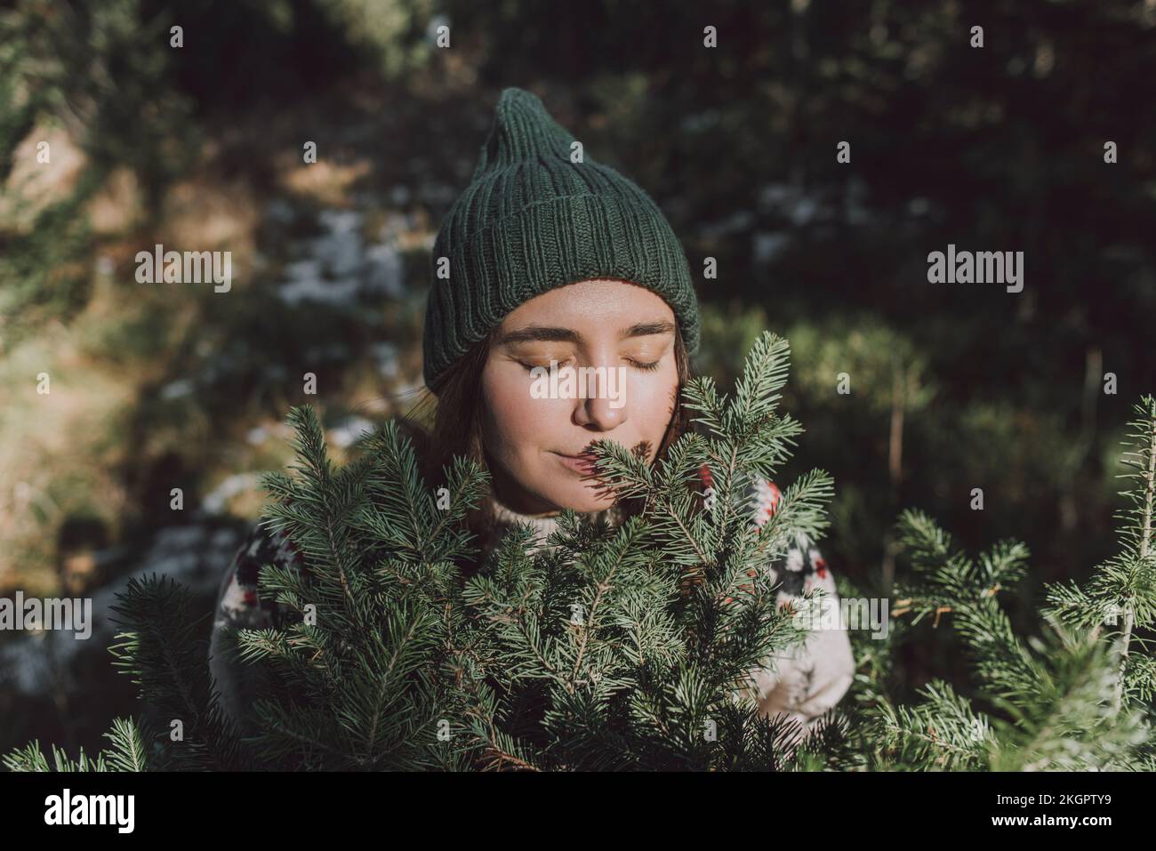 Donna con gli occhi chiusi odoranti ramoscelli di albero sempreverde Foto Stock