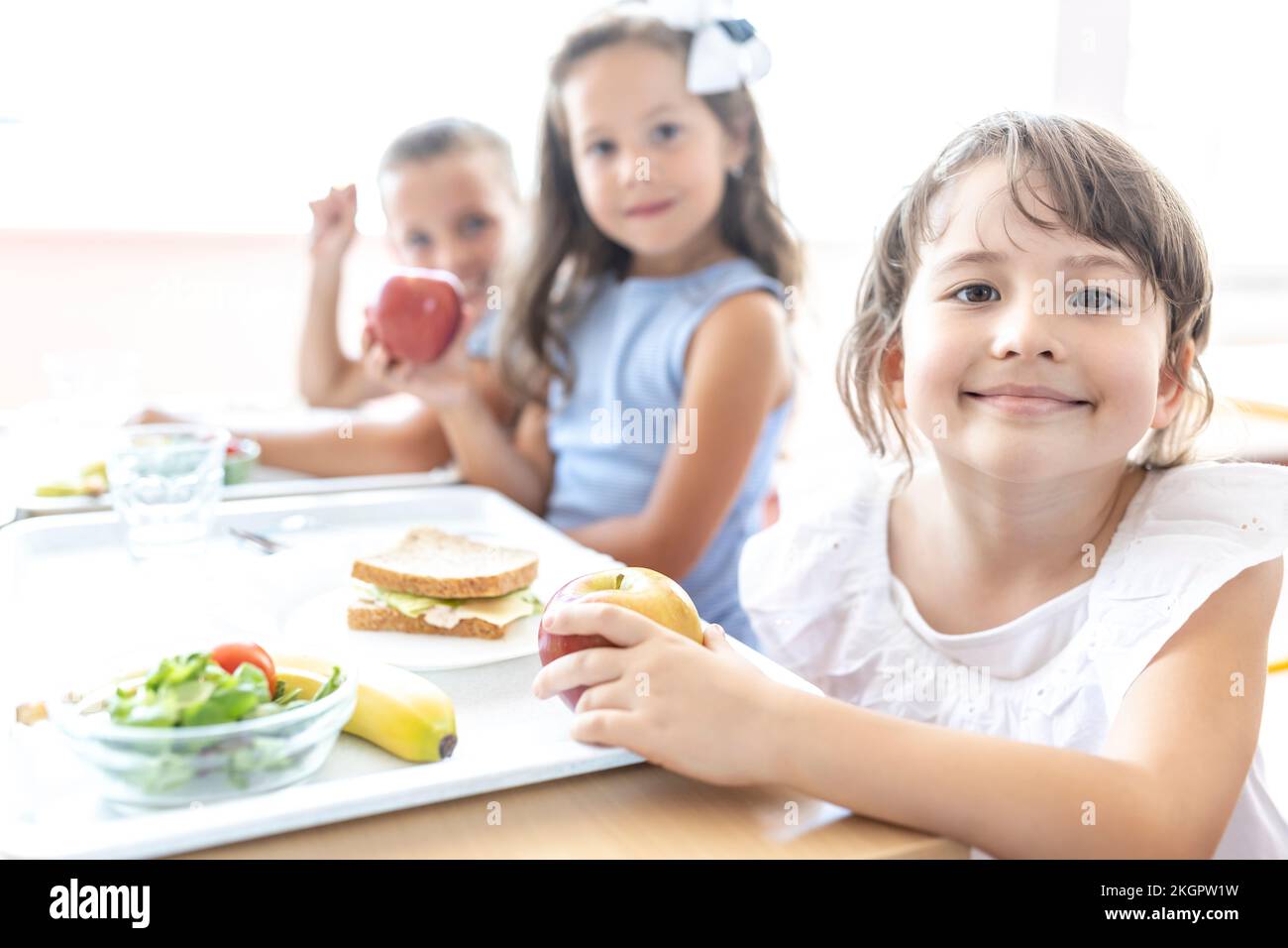 Allievo elementare sorridente con vassoio di cibo sul tavolo durante la pausa pranzo in caffetteria Foto Stock