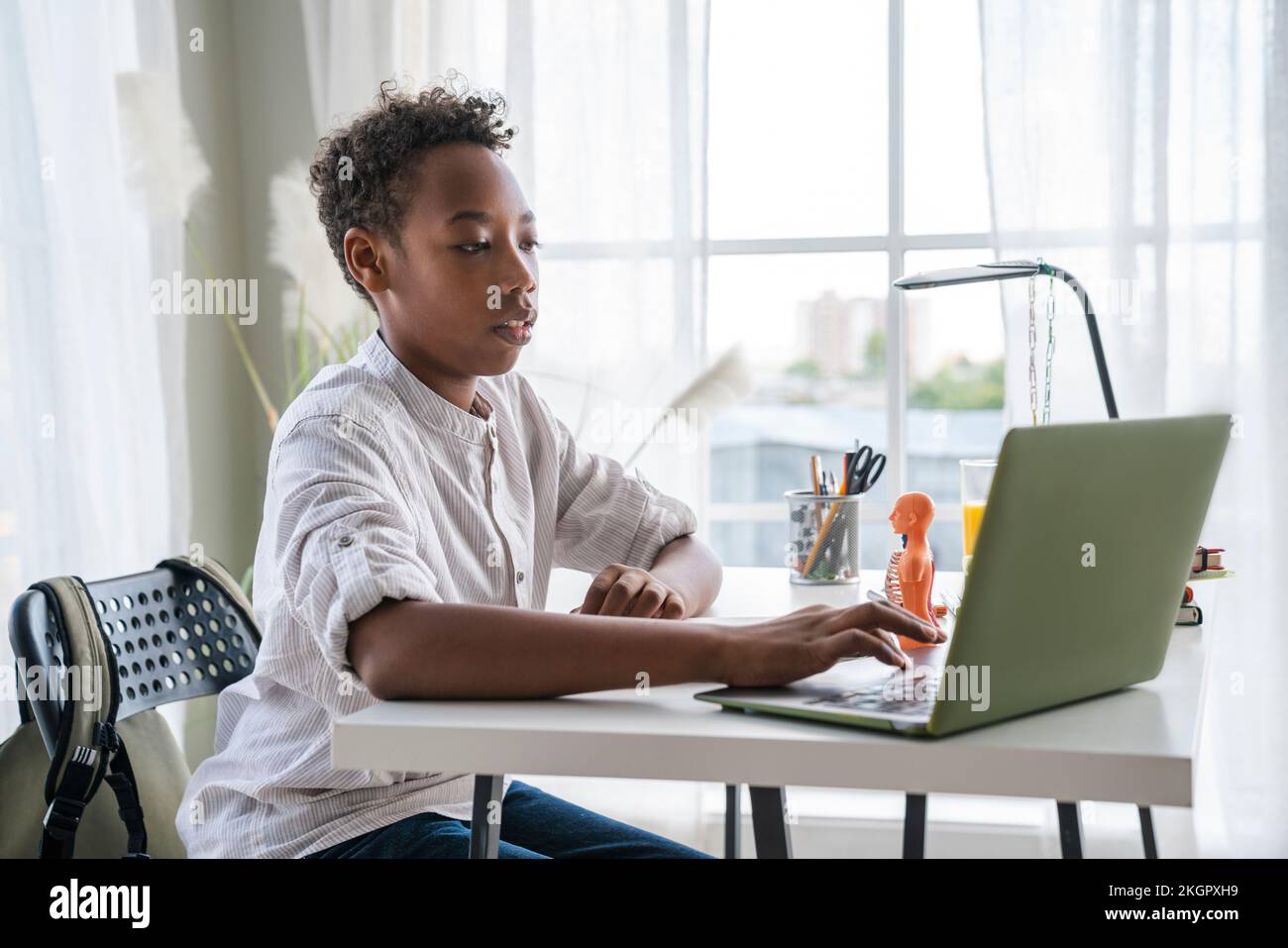 Ragazzo che fa i compiti a scuola usando un notebook a casa Foto Stock