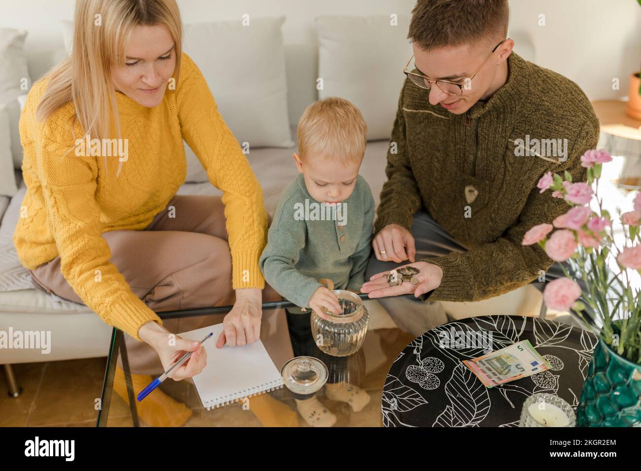 I genitori con figlio contano le monete nel soggiorno a casa Foto Stock
