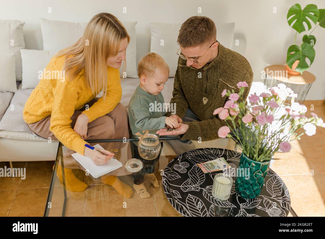 Uomo e donna con figlio che contano monete nel soggiorno di casa Foto Stock
