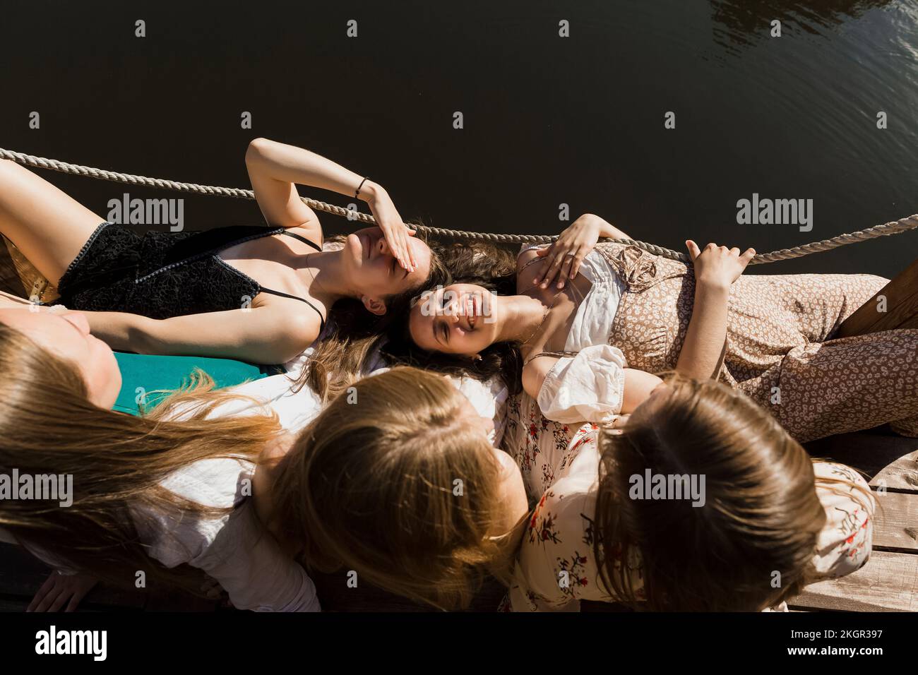 Giovani donne sorridenti sdraiate sul grembo degli amici Foto Stock