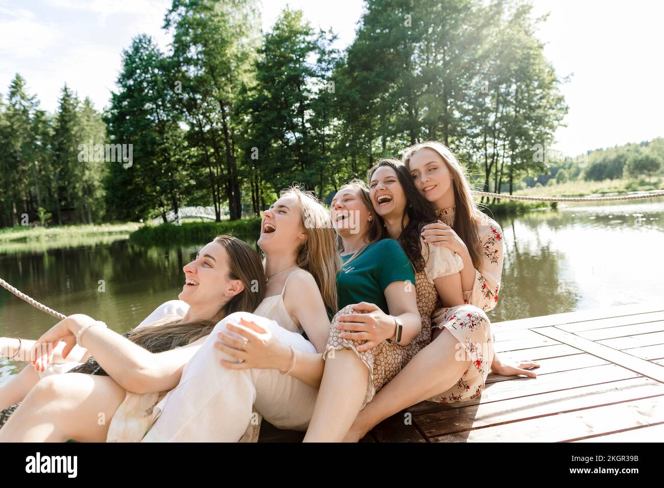Felici amici femminili che si appoggiano l'uno sull'altro al molo Foto Stock
