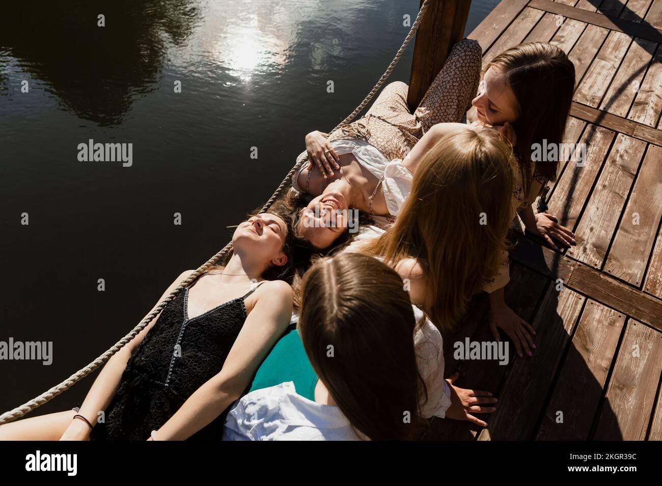 Donne sorridenti sdraiate sul grembo degli amici Foto Stock