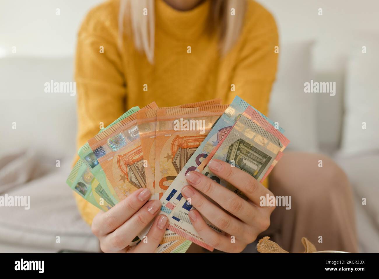 Donna che conta la valuta nel soggiorno a casa Foto Stock
