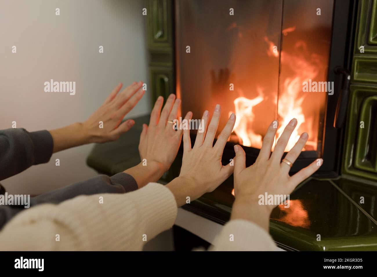 L'uomo e la donna riscaldano le mani di fronte al caminetto a casa Foto Stock