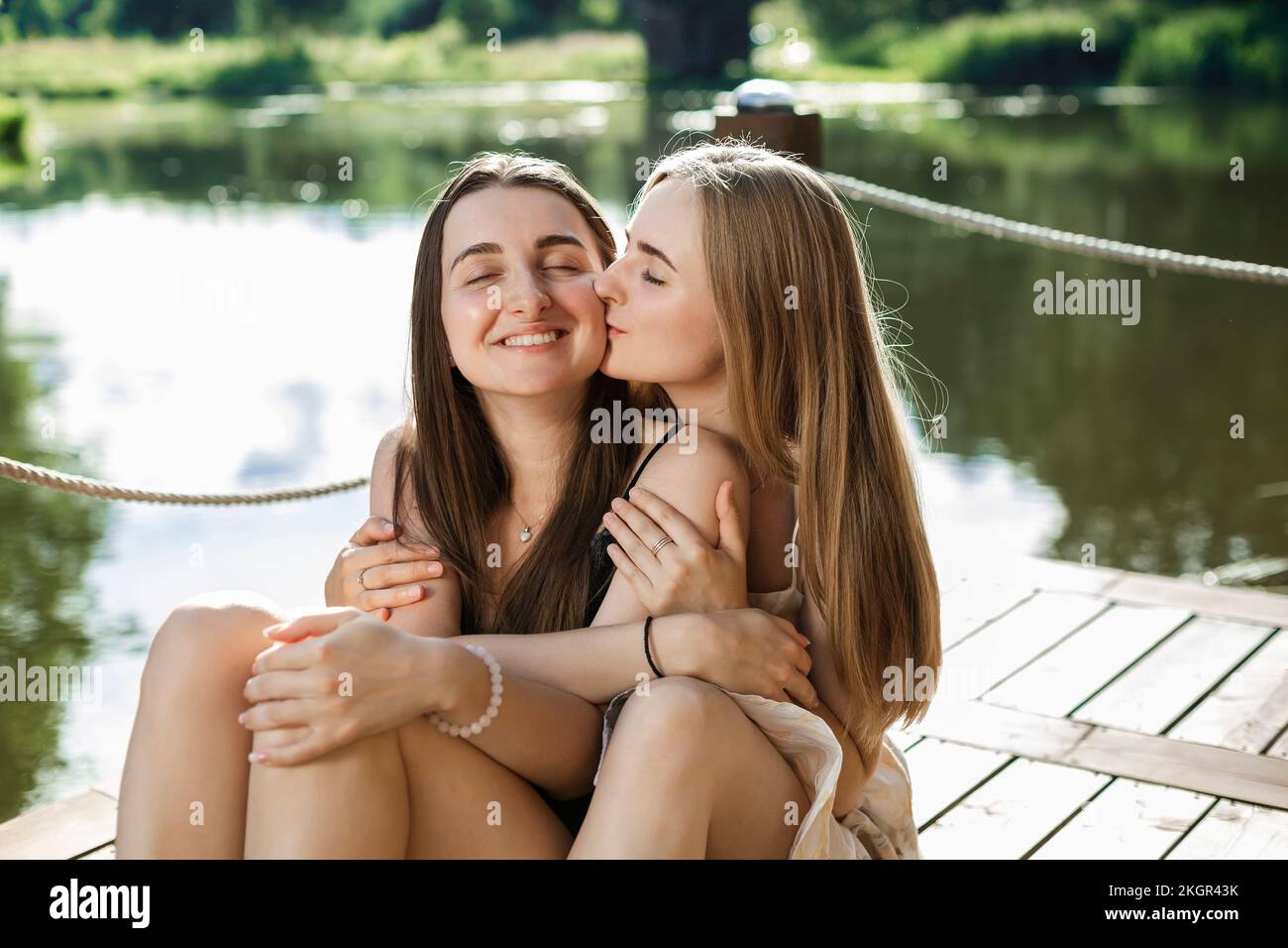 Giovane donna che bacia amico sul molo Foto Stock