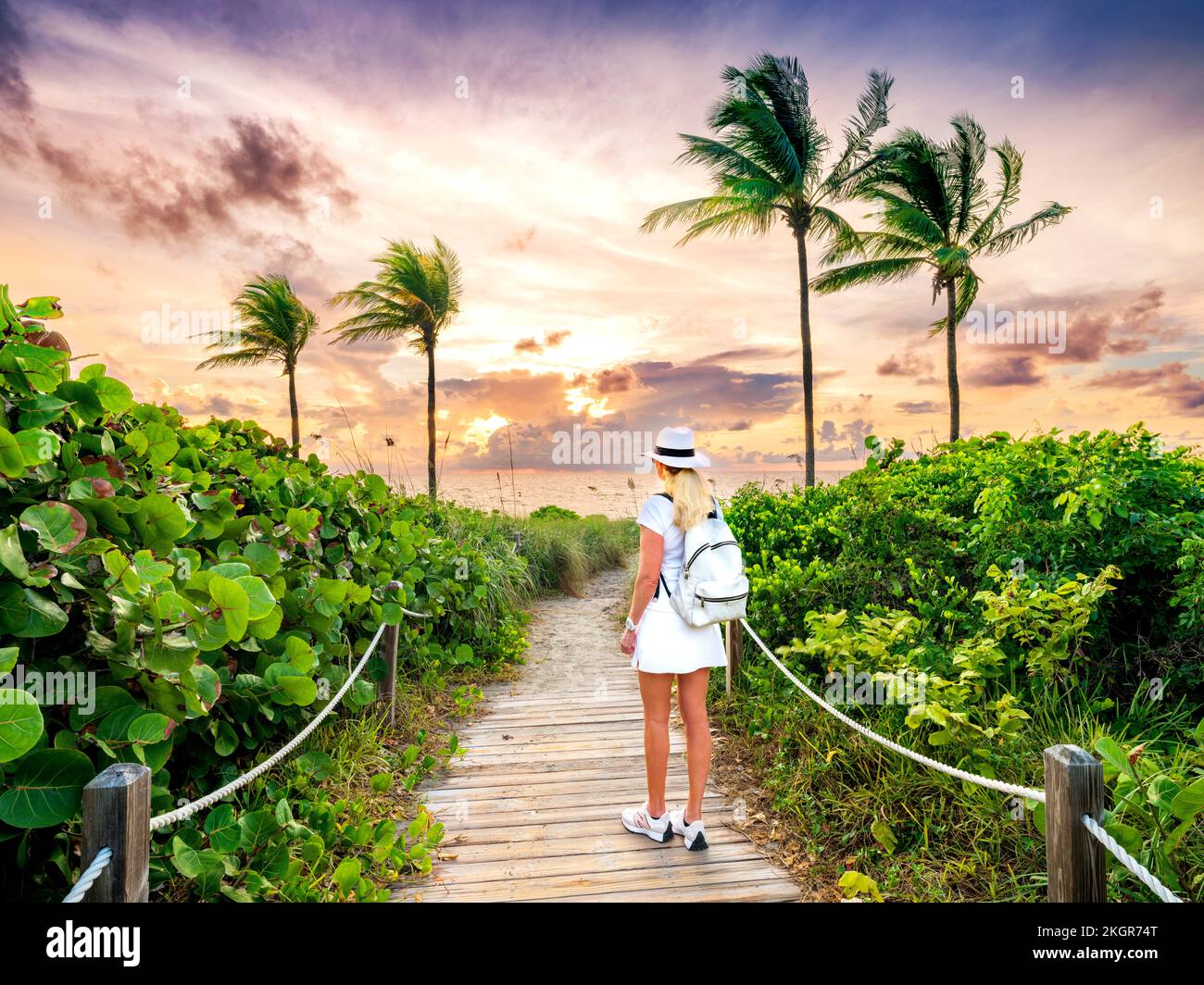 Donna che cammina su b bella eautiful Beach Path incorniciata da Palmtrees che conduce alla spiaggia, Hollywood Beach, Sunrise Miami, South Florida, USA Foto Stock