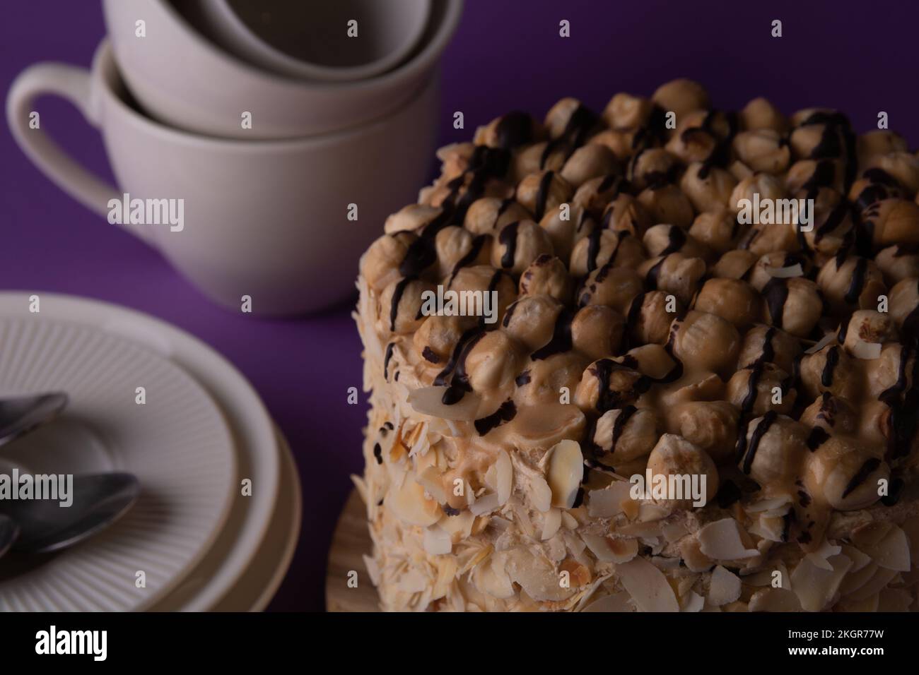 foto torta di noce intera e stoviglie vista laterale su sfondo viola Foto Stock