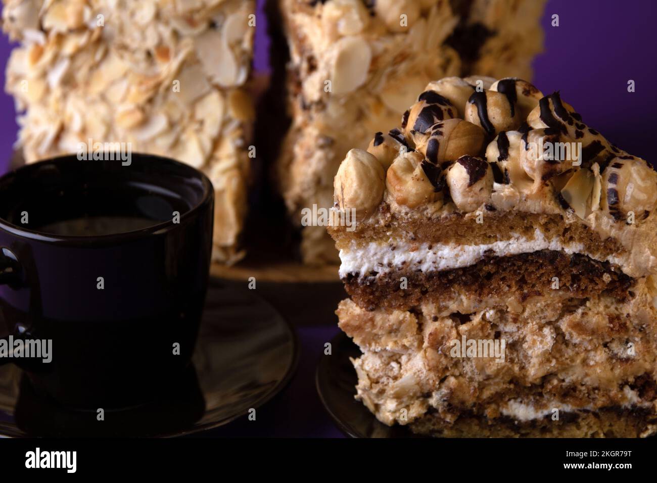 foto fetta di torta su un piattino con una tazza di caffè su sfondo viola Foto Stock