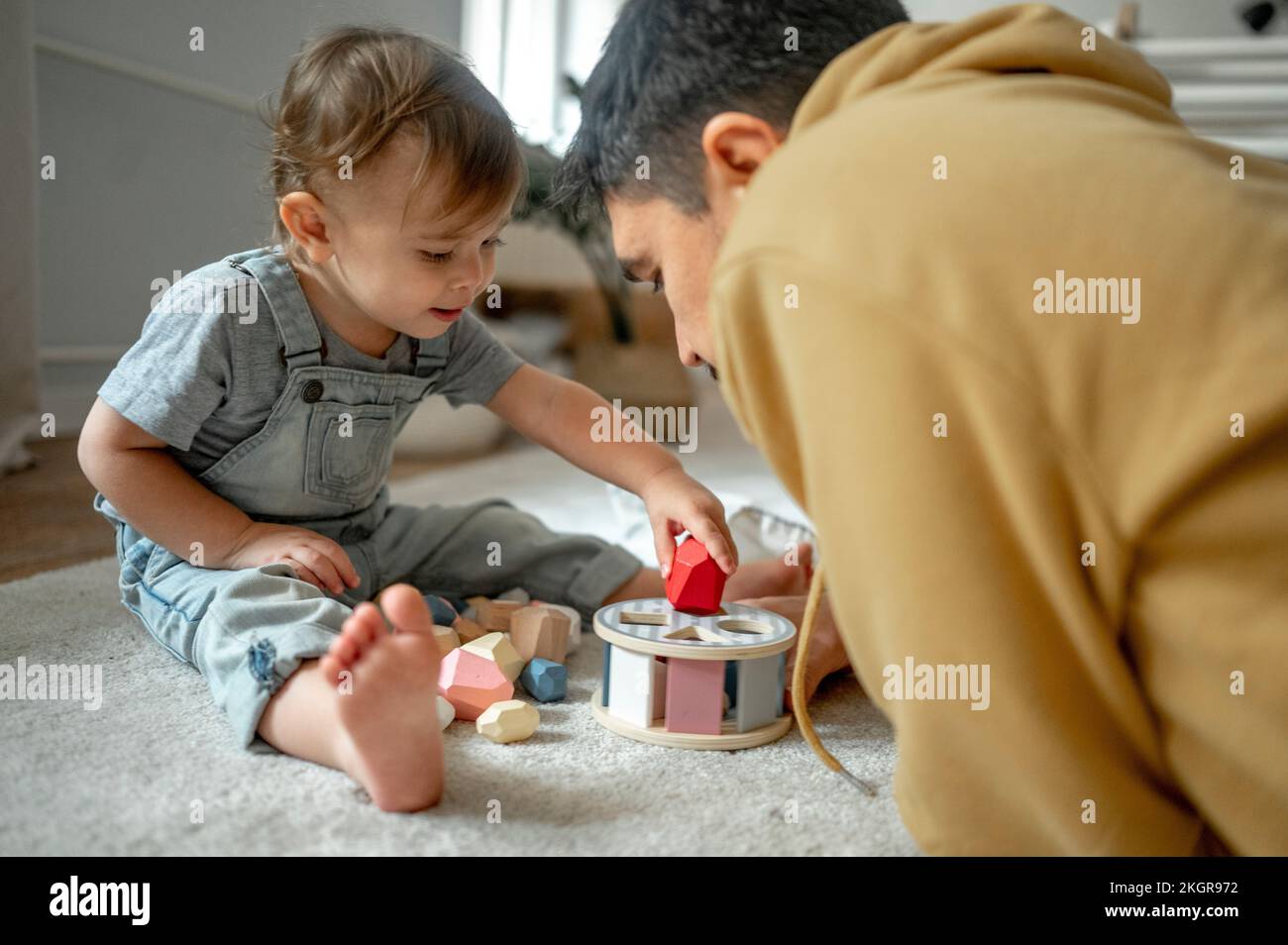 Padre e figlio giocano con giocattoli di legno a casa Foto Stock