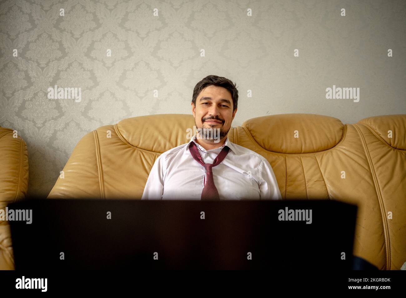 Sorridente freelancer seduto sul divano a casa Foto Stock