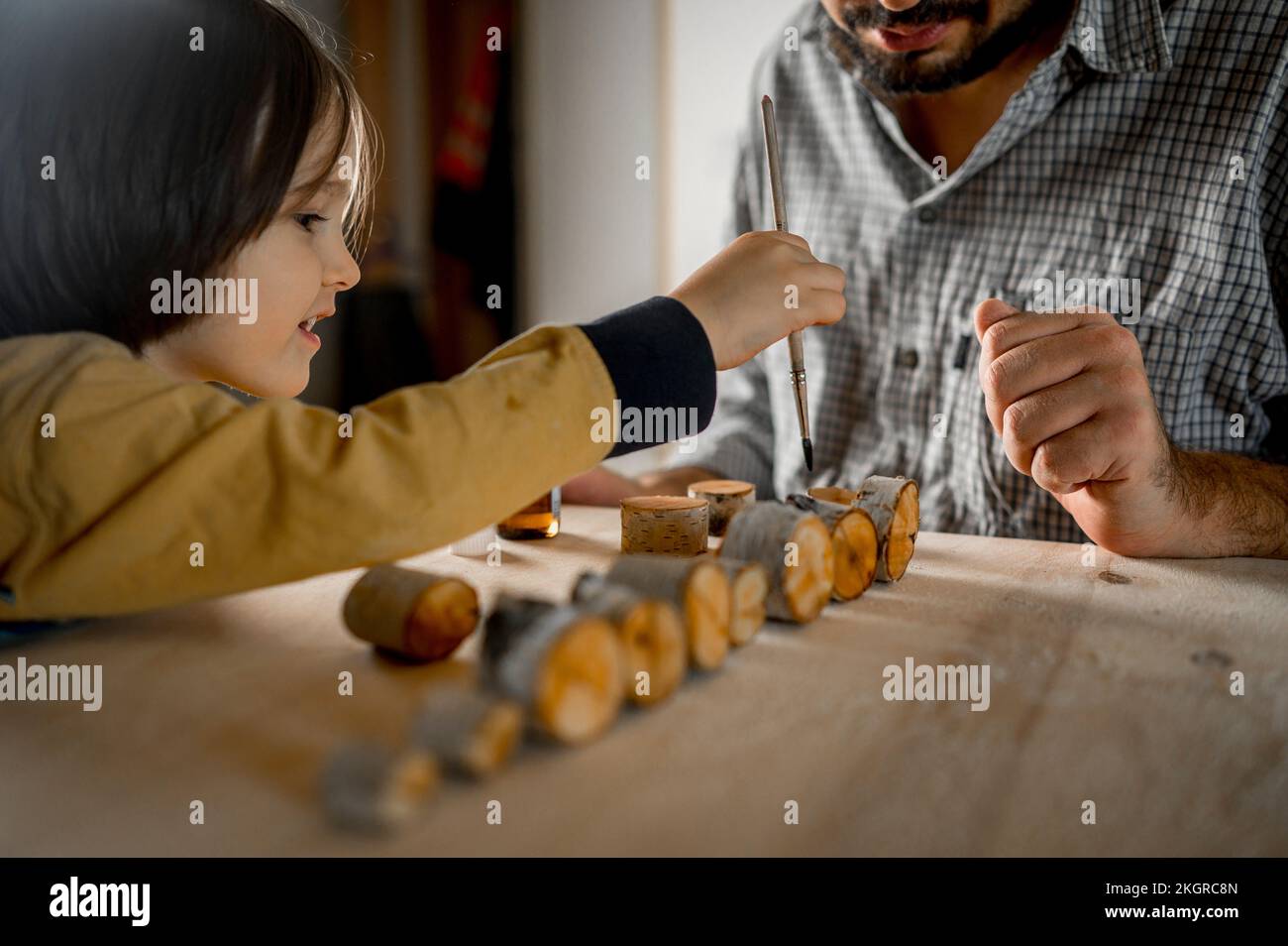 Figlio aiutando padre spazzolando olio su legno Foto Stock