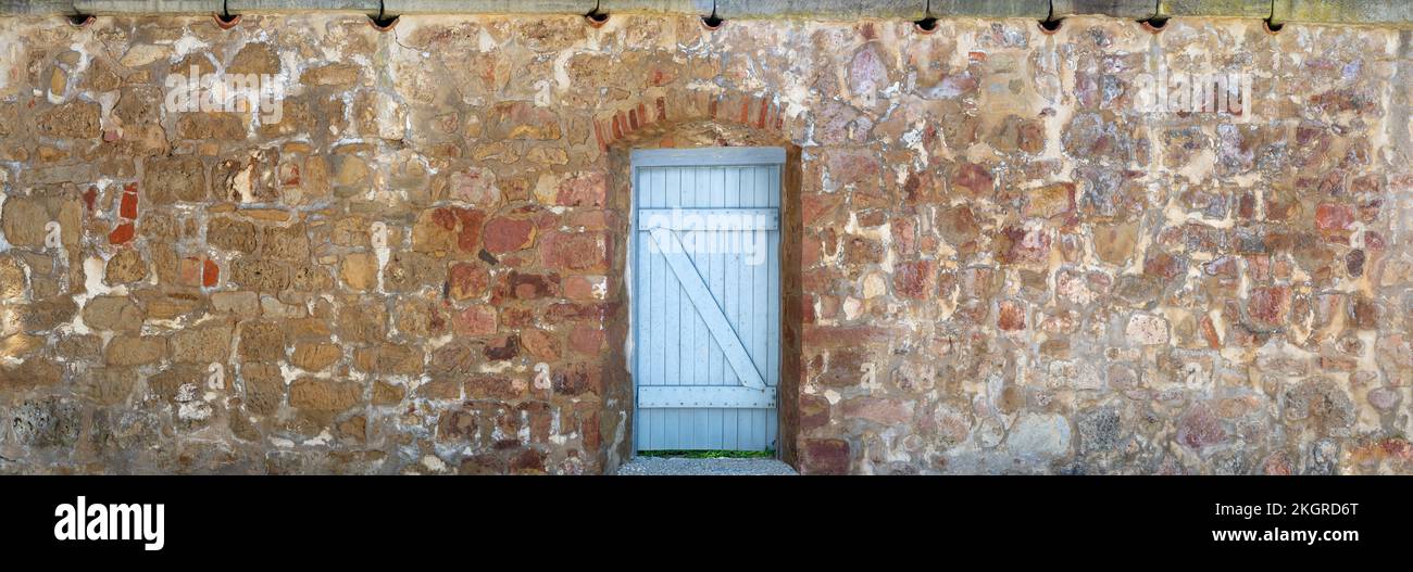 Panorama - Vecchio muro di pietra con porta di legno blu chiaro Foto Stock