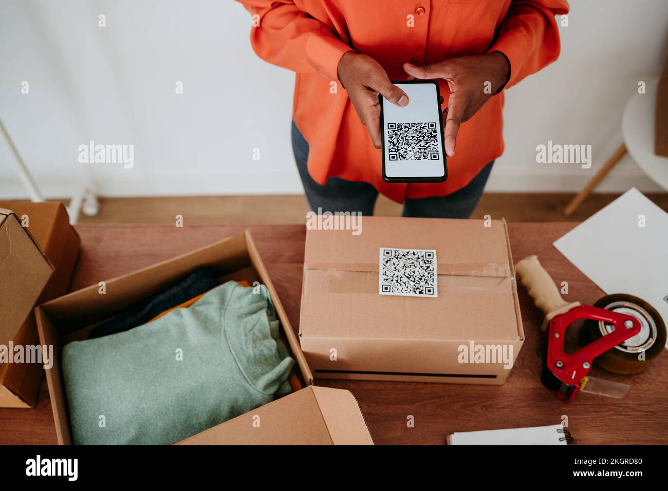Donna d'affari che scansiona il codice QR sulla confezione alla scrivania Foto Stock