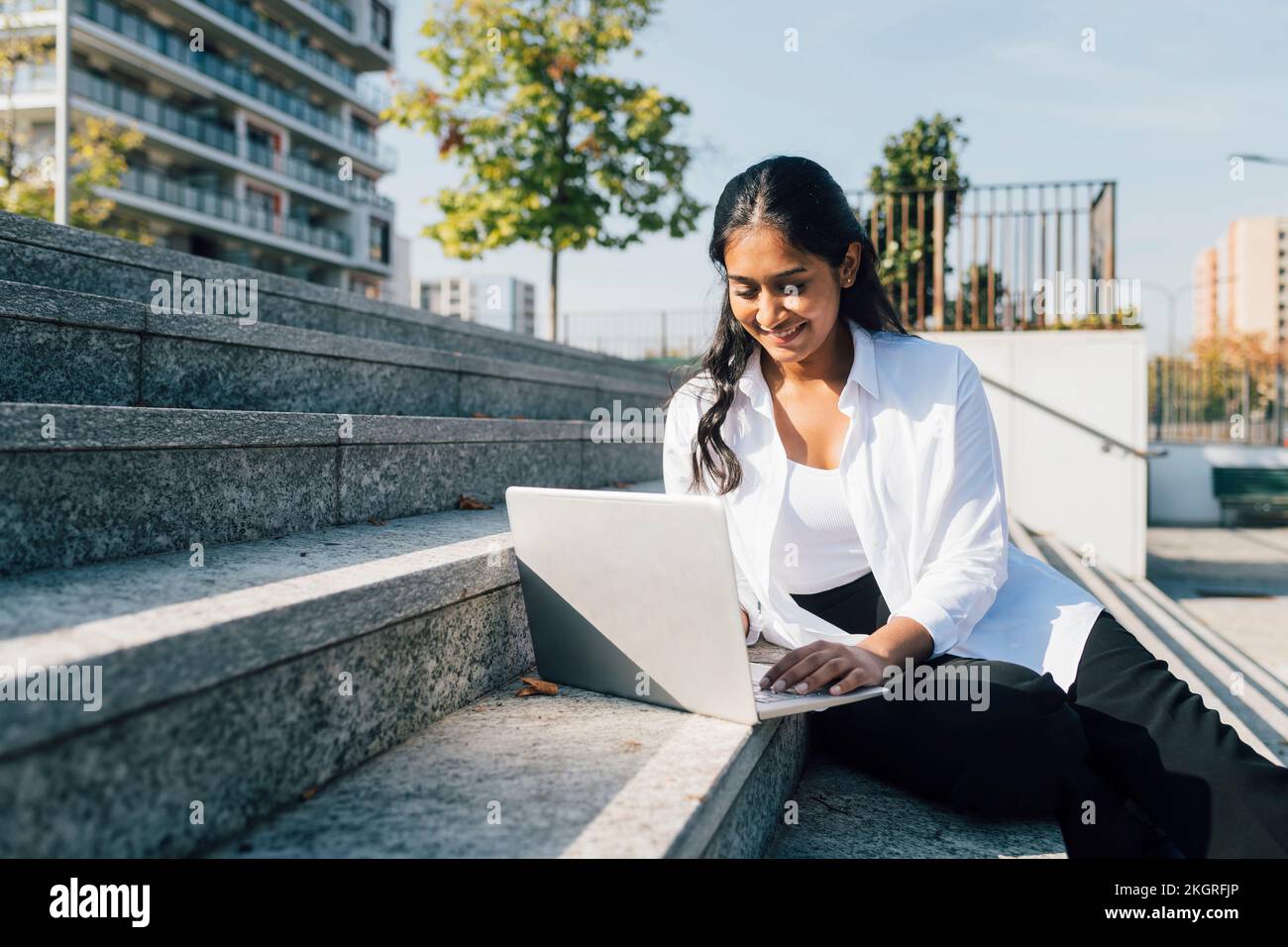 Giovane donna sorridente che usa il notebook per i passi Foto Stock