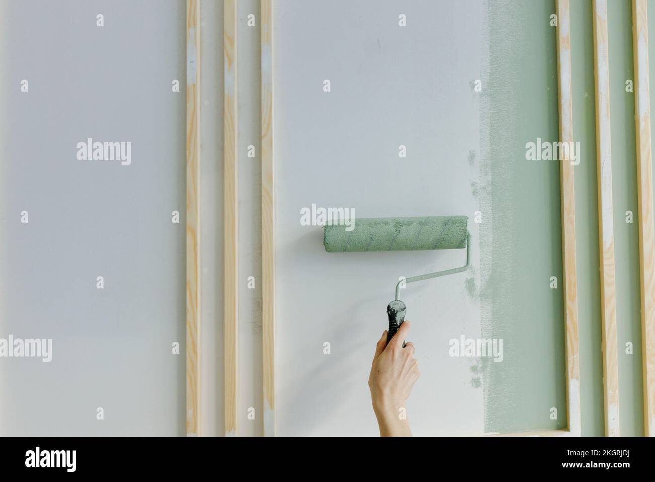 Mano di donna pittura con rullo di vernice sul muro a casa Foto Stock