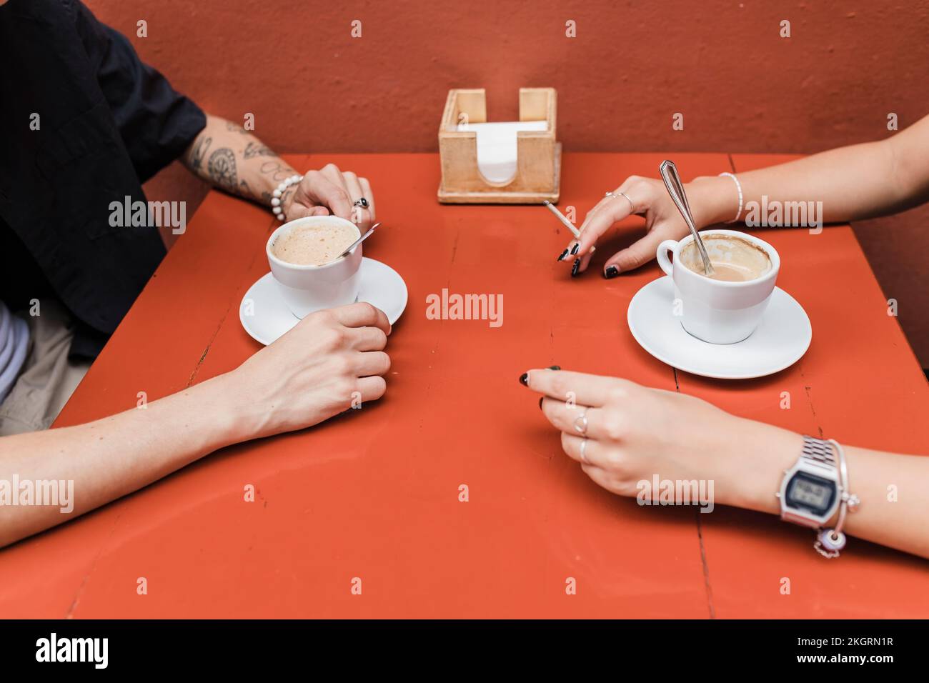 Mano di donna che tiene la sigaretta marijuana congiunta con l'uomo al caffè marciapiede Foto Stock