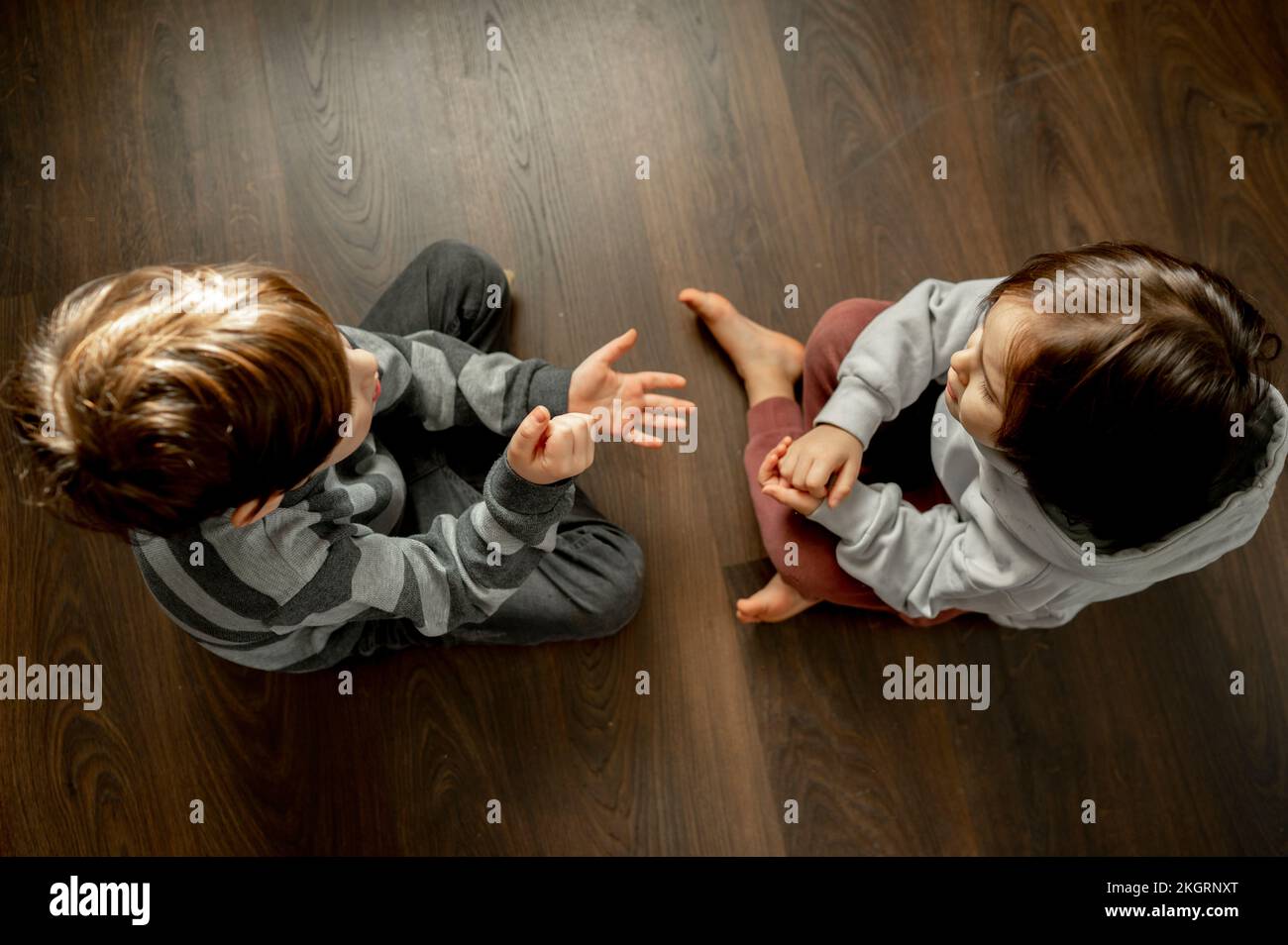 Ragazzo con fratello che gioca a forbici di carta da roccia sul pavimento a casa Foto Stock