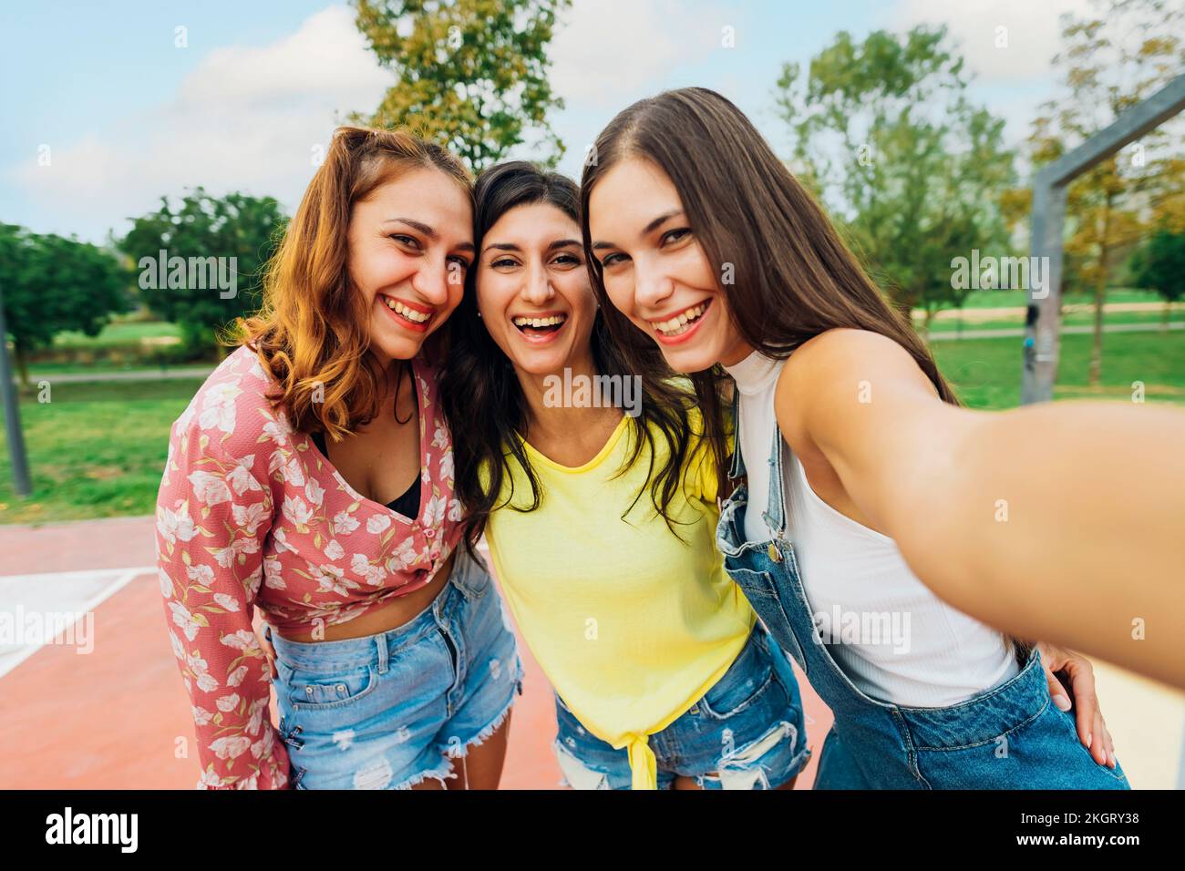 Donna felice con gli amici che prendono selfie al campo sportivo Foto Stock