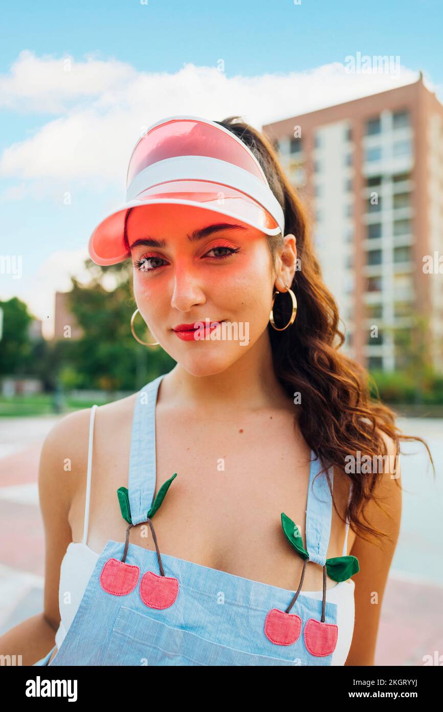 Sorridente bella donna che indossa la visiera parasole in piedi presso il campo sportivo Foto Stock