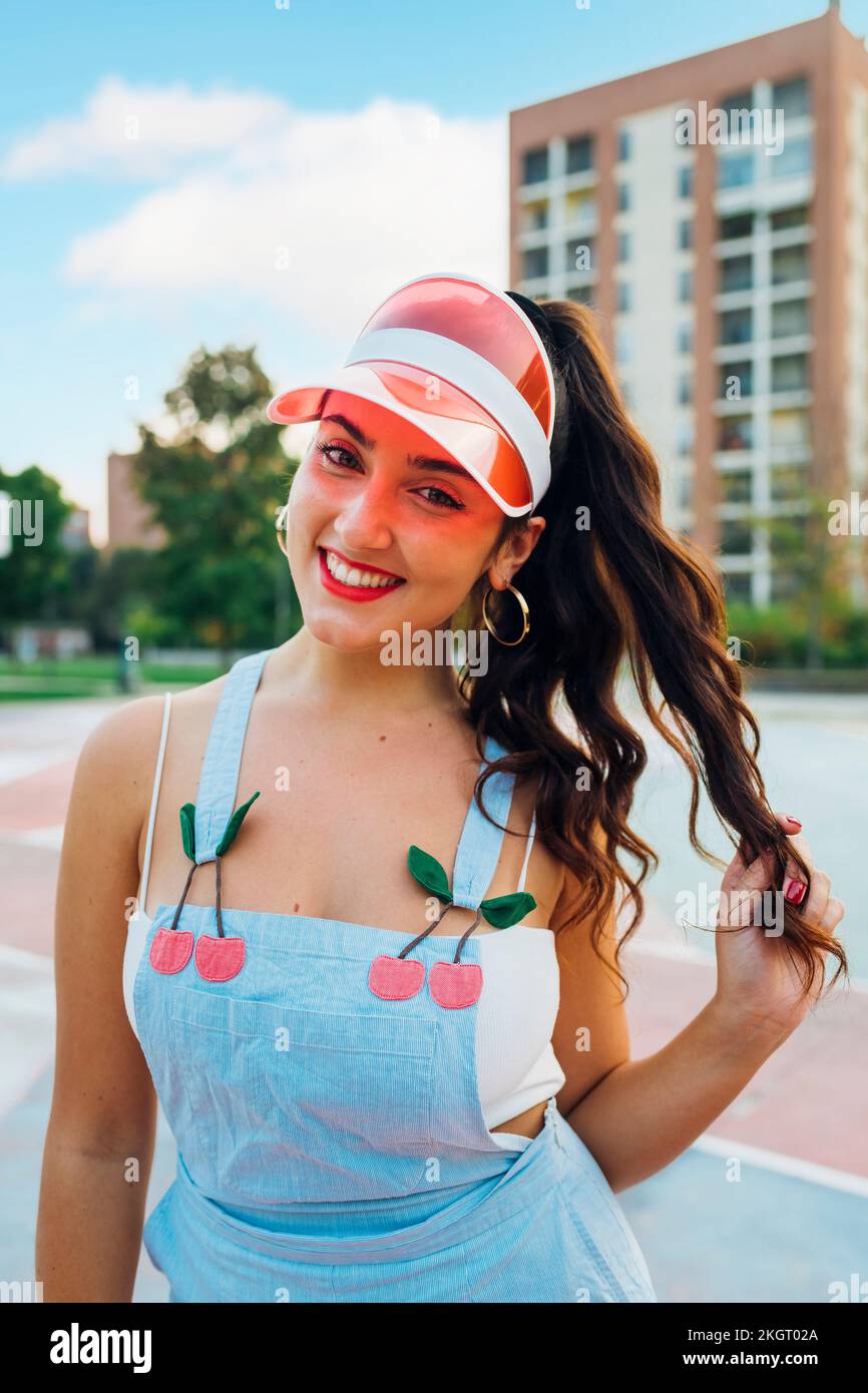 Giovane donna sorridente che indossa la visiera parasole a un campo sportivo Foto Stock