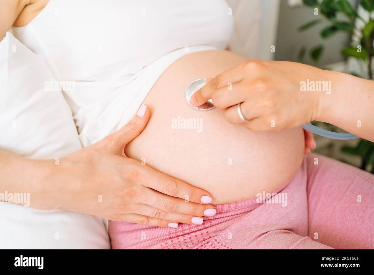 Mano del medico che esamina il ventre di donna incinta con stetoscopio Foto Stock