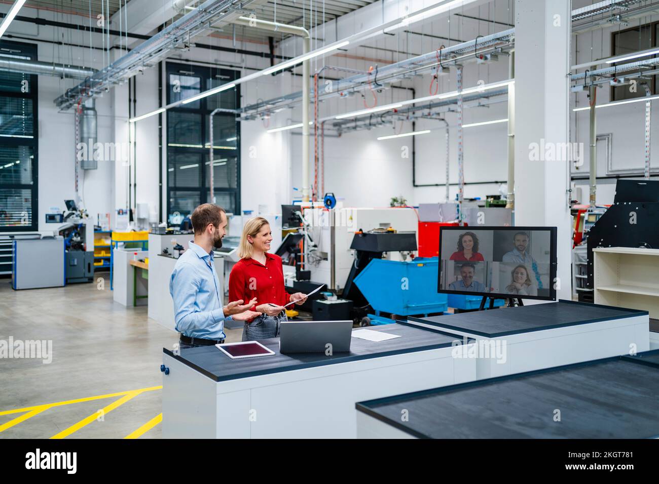 Colleghi di lavoro felici che fanno la videochiamata sullo schermo del computer in fabbrica Foto Stock