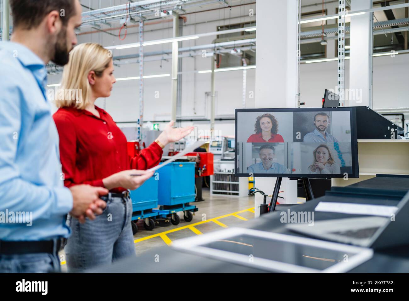 Donna d'affari gesturing da collega sopra la videochiamata sullo schermo del calcolatore alla fabbrica Foto Stock