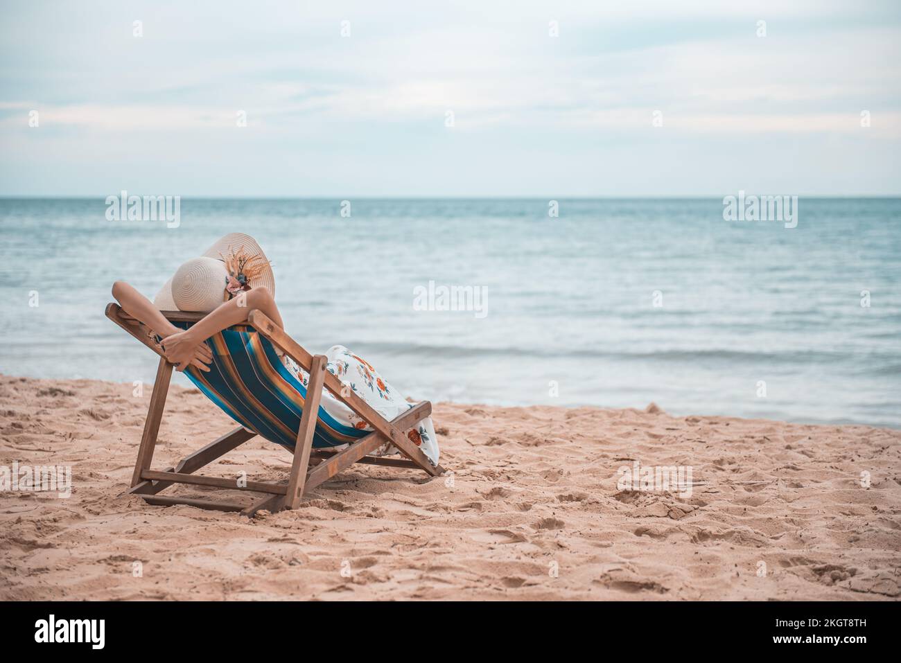 Bella giovane donna asiatica con braccio cappello su rilassante su sedia da spiaggia, estate felice vacanza spiaggia concetto. Foto Stock