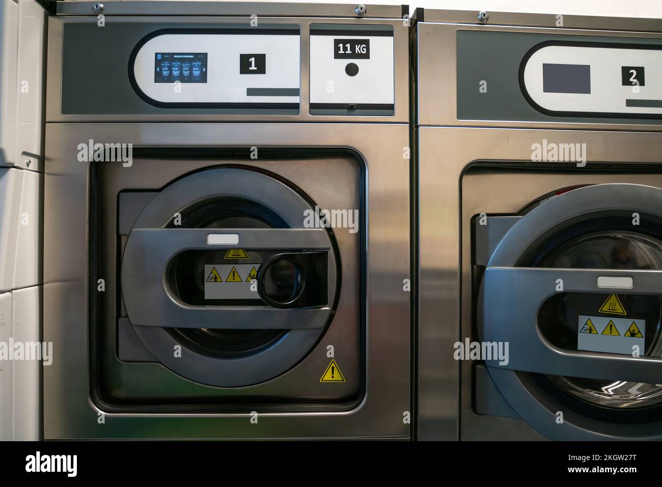 Due lavatori a carico anteriore su una lavanderia pubblica Foto Stock