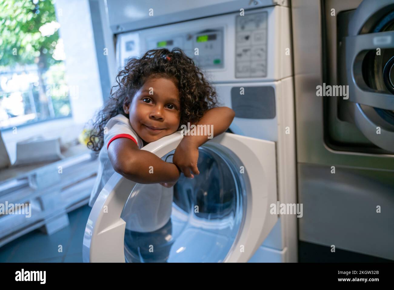 Bambina che scava il tempo in una lavanderia pubblica Foto Stock