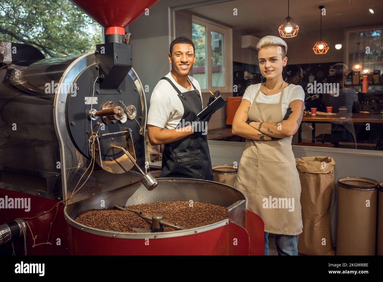 Maestri arrosti sorridenti in piedi in una struttura di tostatura del caffè Foto Stock