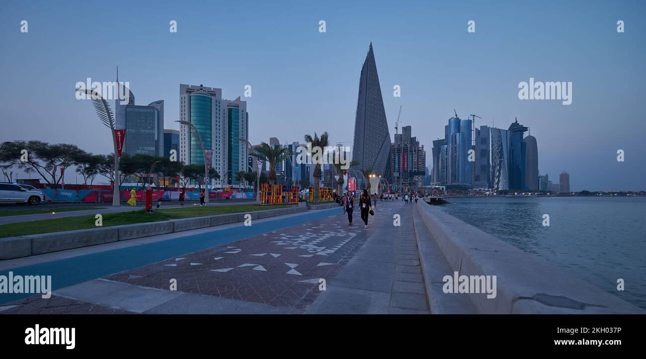 Il tramonto sulla Corniche di Doha mostra il Qatar durante la Coppa del mondo FIFA Qatar 2022 con gente del posto e visitatori che camminano sul lungomare Foto Stock