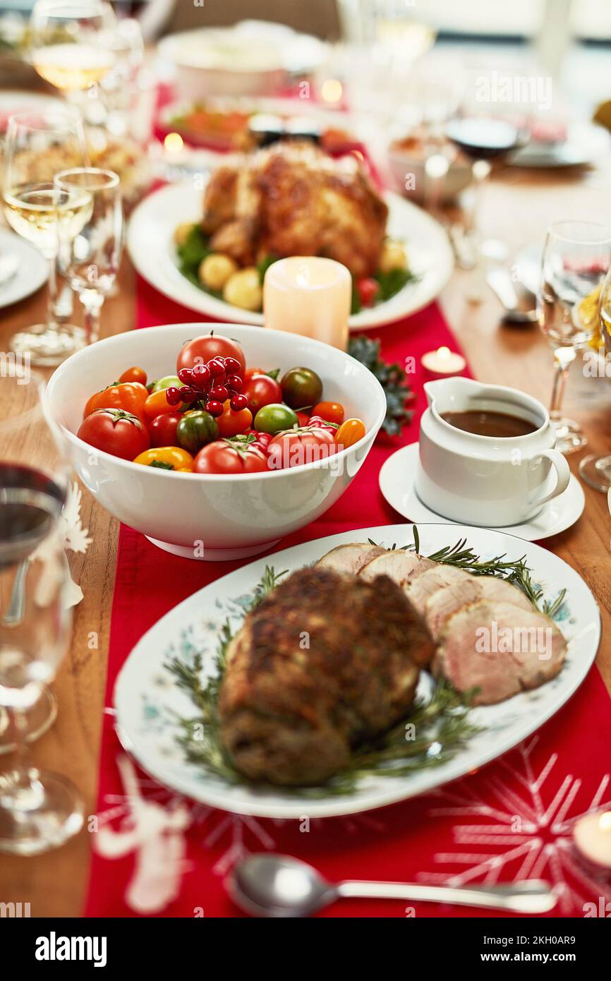 Natale, cena e cibo su un tavolo per festa con arrosti, carne e verdure in casa. Non c'è gente, sala da pranzo e pasto festivo per Natale Foto Stock