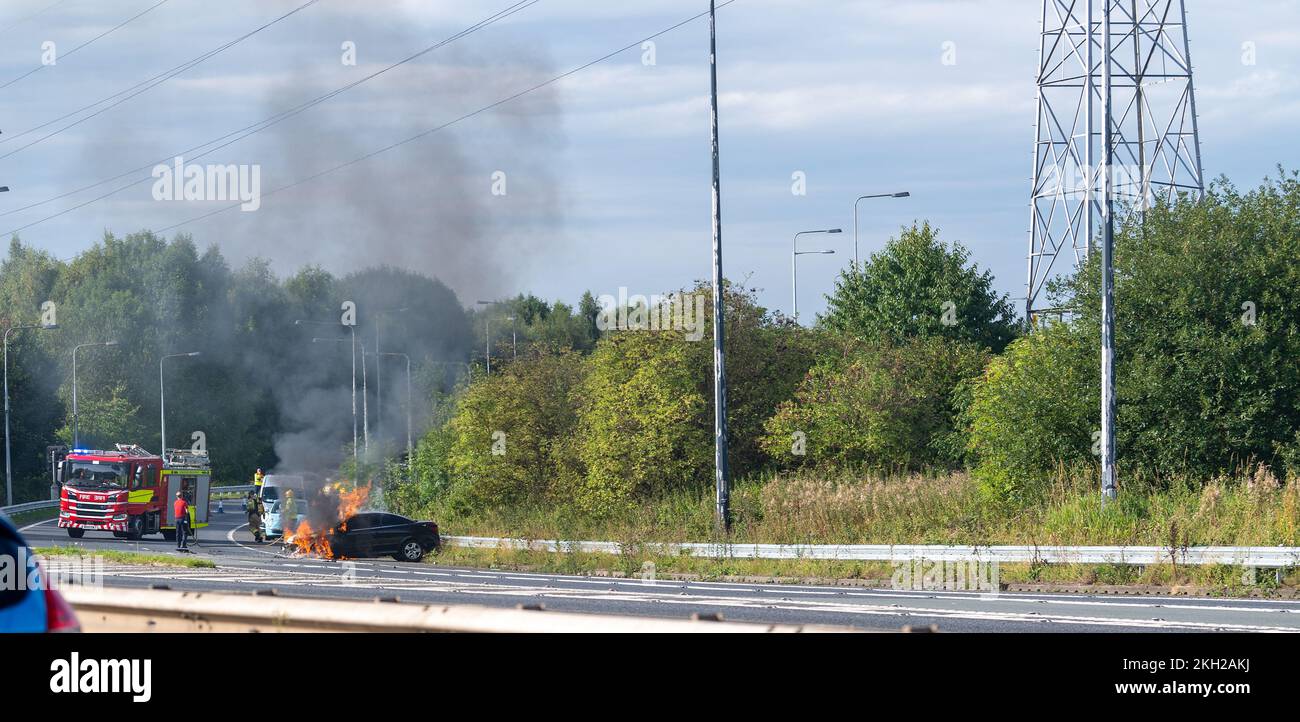 Equipaggio antincendio che mette fuori un incendio di auto dopo un incidente sull'autostrada, Regno Unito. Foto Stock