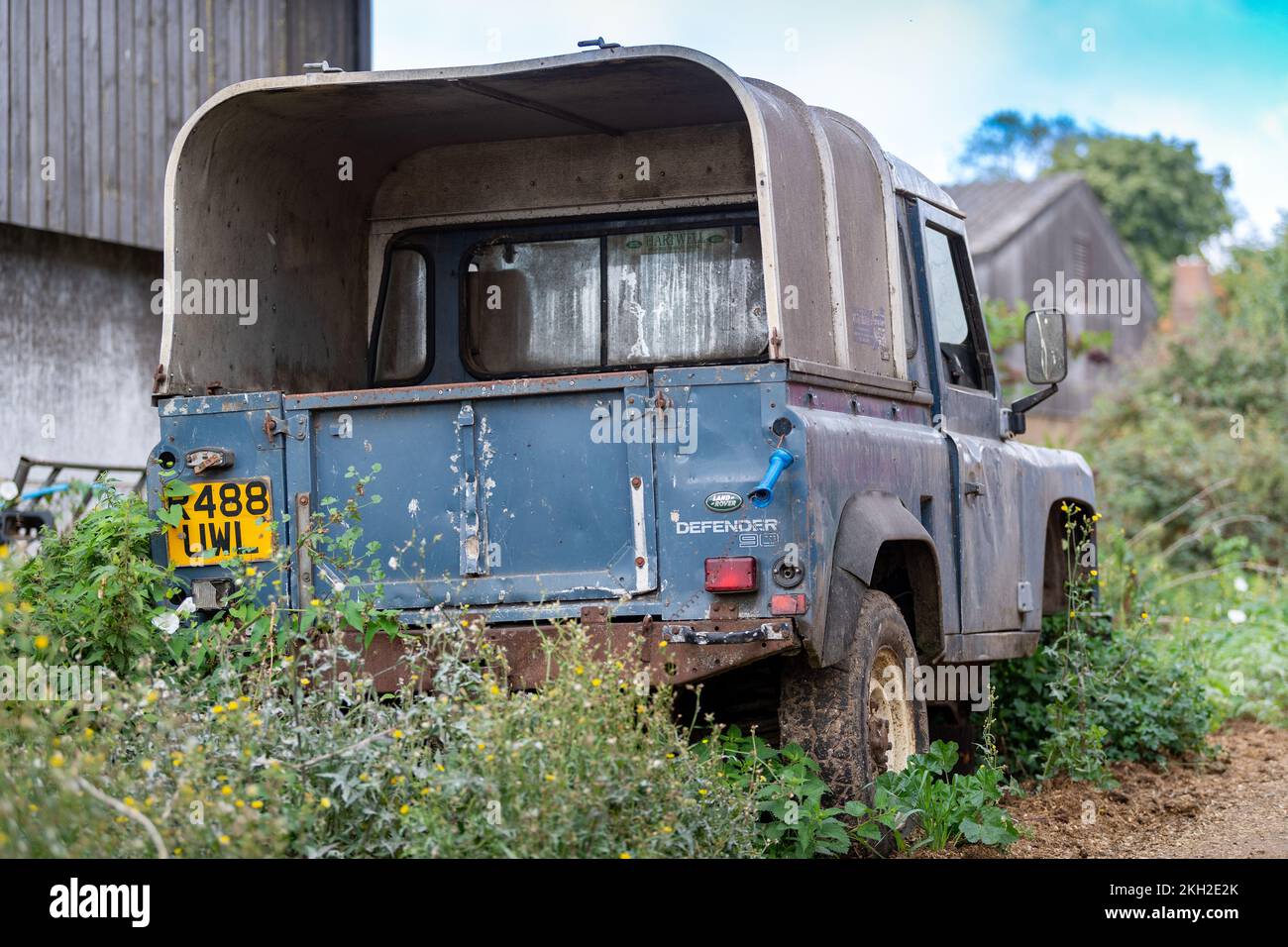 La vecchia Land Rover si è lasciata sul bordo di un cortile agricolo tra bramoli e erbacce. REGNO UNITO. Foto Stock