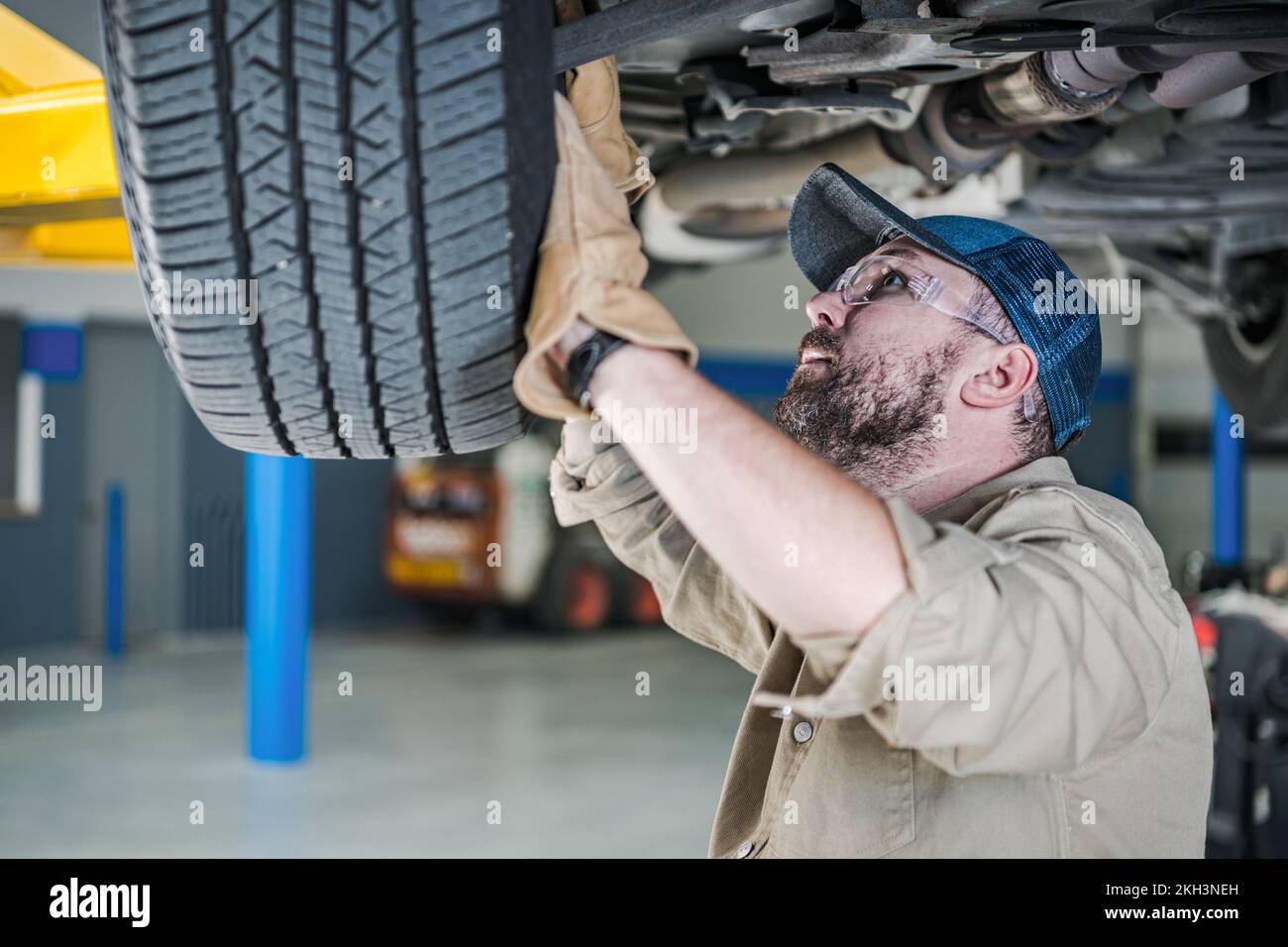 Caucasian Professional Automobile Mechanic Performing Car Suspension Safety Check. Tema di manutenzione del veicolo. Foto Stock